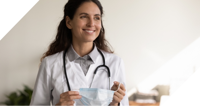 smiling doctor looking away with mask in hand